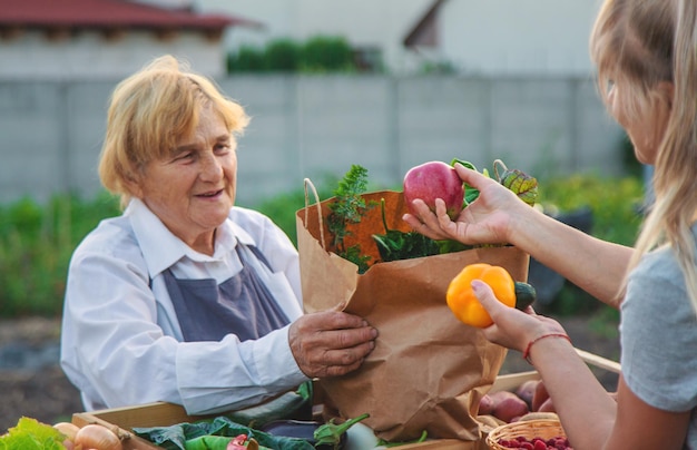 Photo old woman farmer sells vegetables and fruits at the farmers market selective focus food