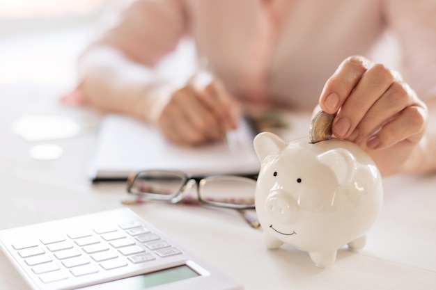 Photo old woman hands put money coins in a piggy