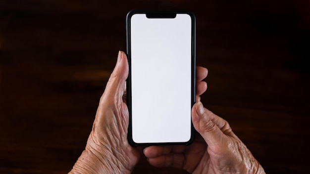 Old woman at home using a mobile phone with white screen Mockup device