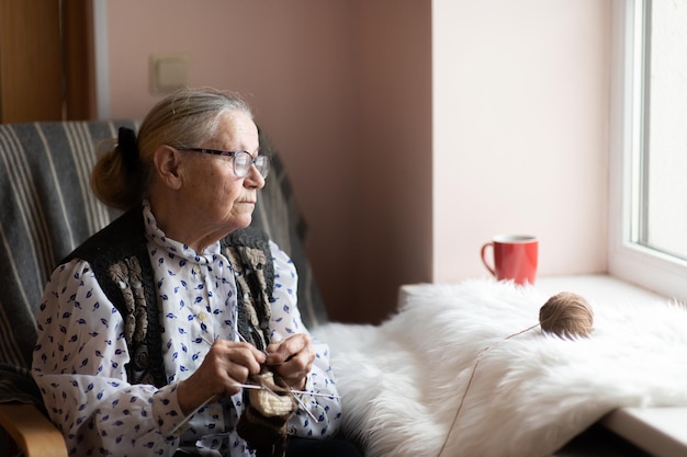 Old woman knitting in a nursing home by the window