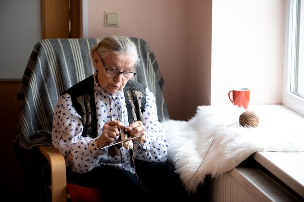 Old woman knitting in a nursing home by the window