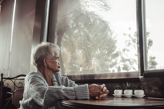 Photo old woman looking through window at home concept loneliness dementia abuse sadness