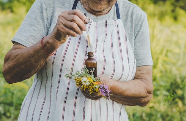 Old woman makes herbal tincture Selective focus