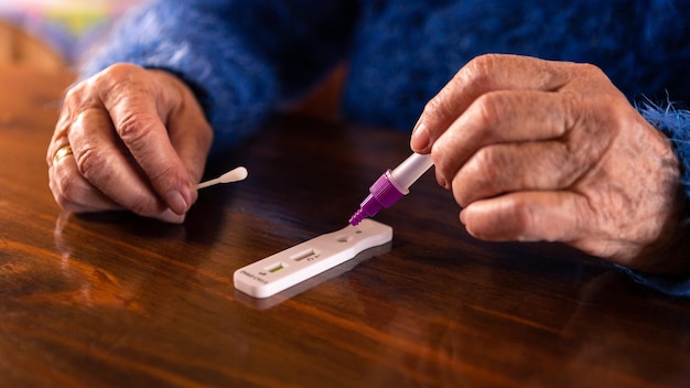 Donna anziana che inserisce il campione nel dispositivo per il test diagnostico dell'antigene covid19