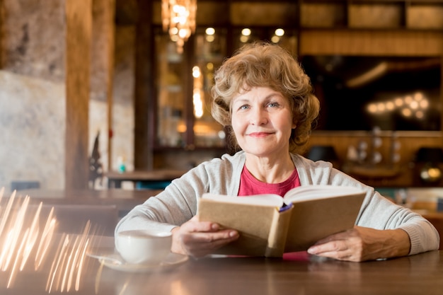 Old woman reading a book in a cafe