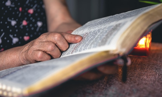 Старуха читает Библию руками крупным планом