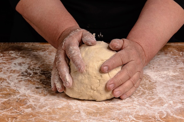 An old woman's grandmother is kneading a dough for cooking bread