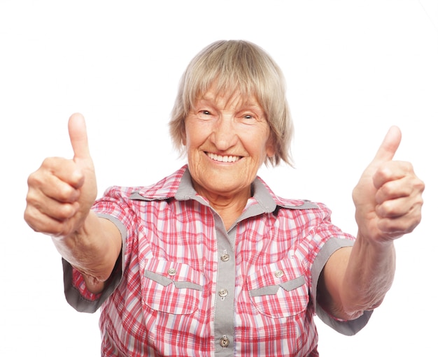 Donna anziana che mostra segno giusto su un bianco