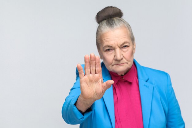 Foto vecchia donna che mostra il segnale di stop alla telecamera