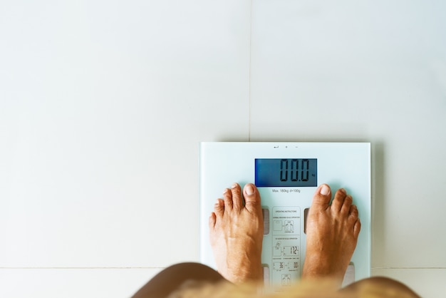 Old woman standing on weight scale white color