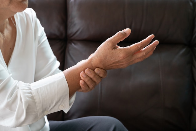 Foto anziana che soffre dal dolore della mano del polso, concetto di problema sanitario
