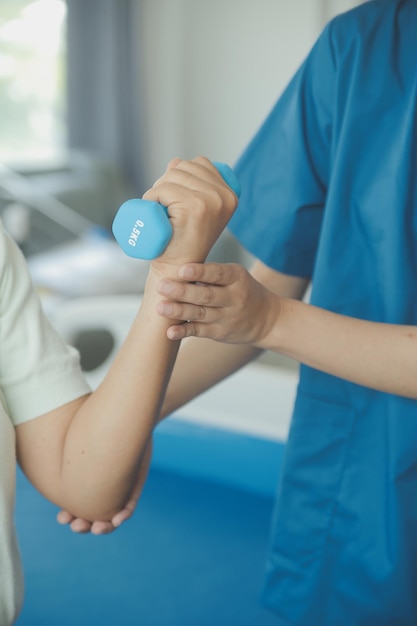 old woman training with physiotherapist using dumbbells at home therapist assisting senior woman with exercises in nursing home elderly patient using dumbbells with outstretched arms