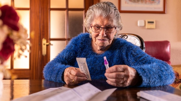 Old woman unpacking coronavirus test kit at home Grandma using a rapid test