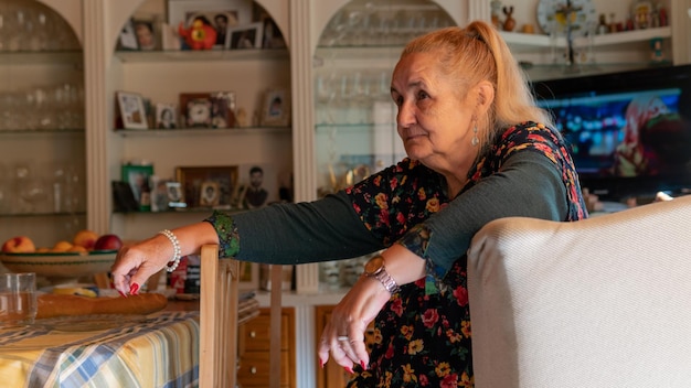 Foto vecchia donna con un vestito nero con fiori nonna seduta vista frontale