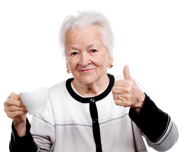 Old woman with a cup of coffee or tea and showing yes sign isolated