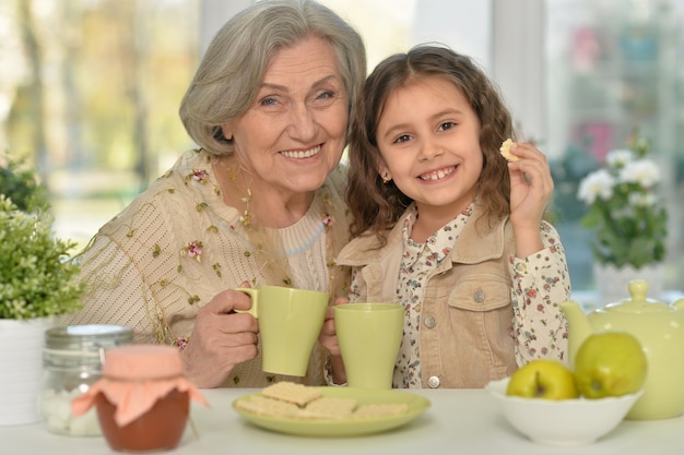 Old woman with a young girl drinking tea