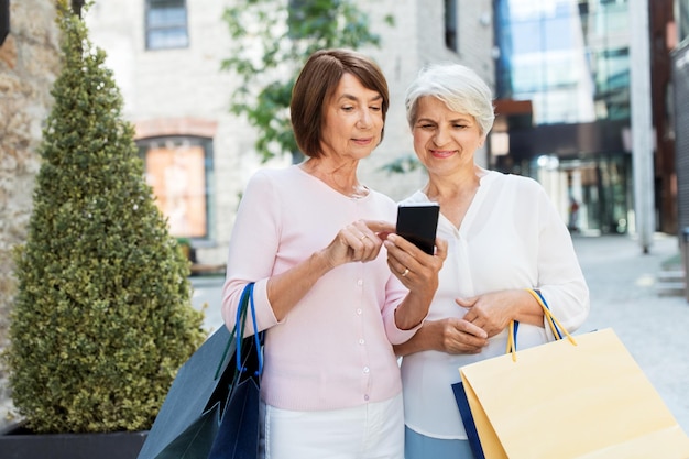 old women with shopping bags and cellphone in city