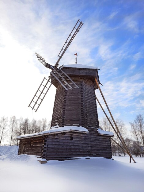 村の古い木の冬の雪に覆われた伝統的な風車