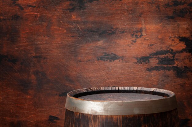 Old wooden barrel for wine or whiskey aging In front of wooden wall with copy space for display your product