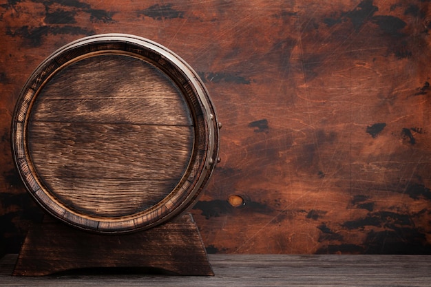Old wooden barrel for wine or whiskey aging In front of wooden wall with copy space