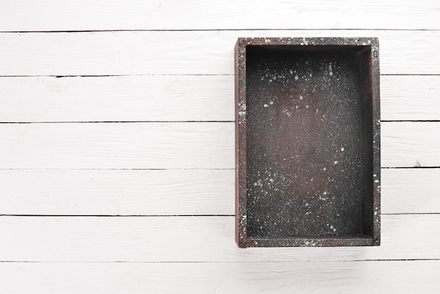 Old wooden black box On a white wooden background Top view Free copy space