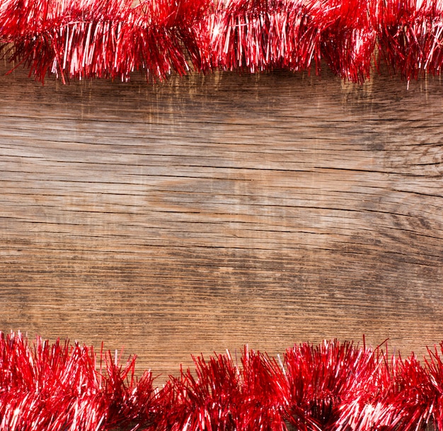 Old wooden boards framed by red tinsel. New Year, Christmas background with space for text.