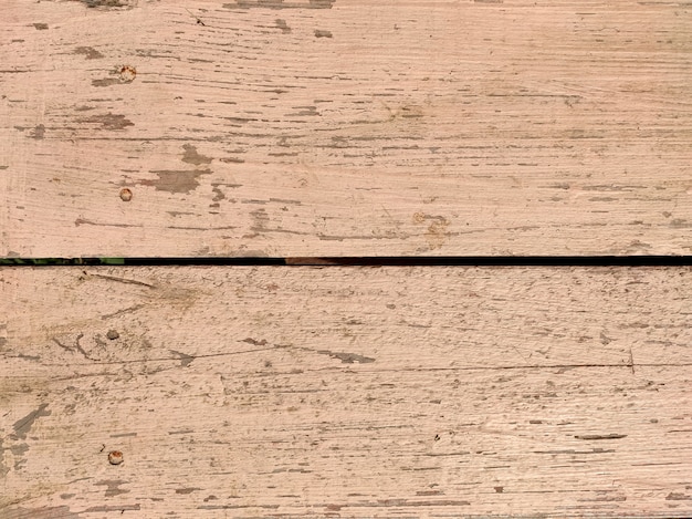 Old wooden boards with beige peeling paint with cracks. Rough surface texture.