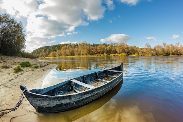 Old wooden boat on the bank of a wide river in sunny day