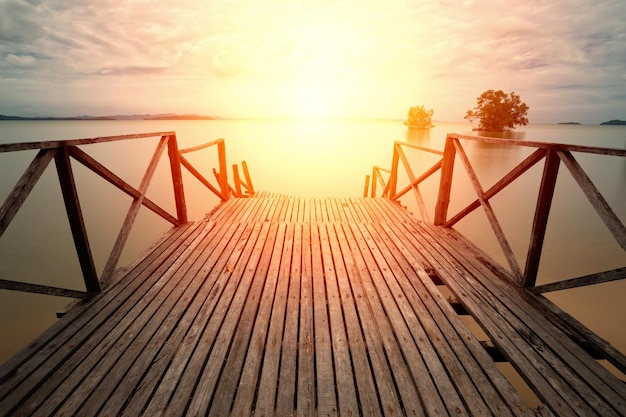 Foto vecchio ponte di legno sulla spiaggia che porta al mare al tramonto molo sul mare contro il cielo durante il tramonto