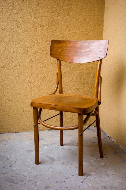 Old wooden chair on yellow wall background