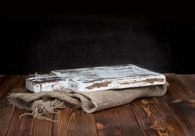 Old wooden chopping board with burlap tablecloth