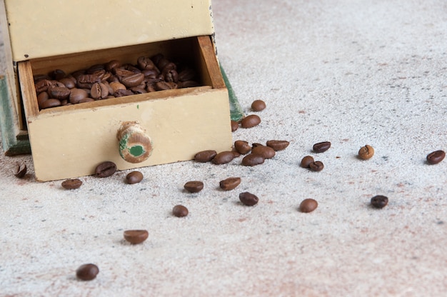 Old wooden coffee grinder on concrete background. 