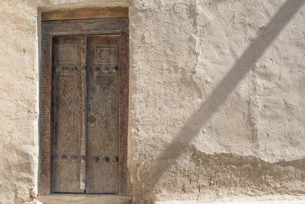 Old wooden door and exfoliating wall in the historic city, Central Asia