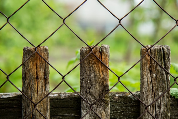 Old wooden fence in the garden and metal mesh