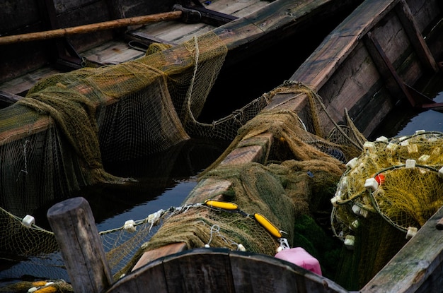 Old wooden fisherman boat with a paddle Inside is a fishing net and other fishing gear A good way to make money for the villagers Boat fills with water