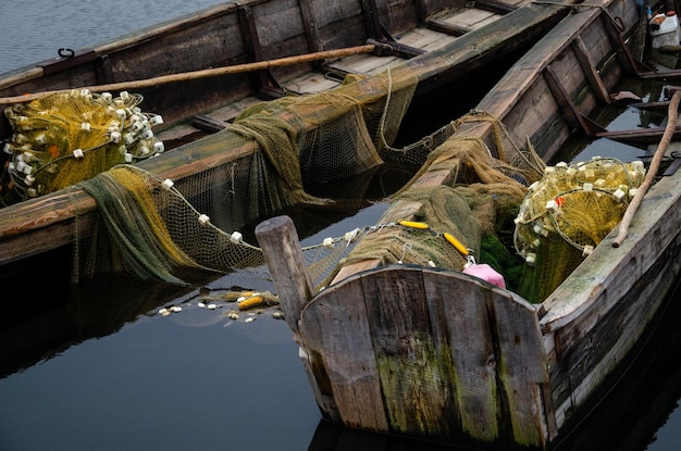 Photo old wooden fisherman boat with a paddle inside is a fishing net and other fishing gear a good way to make money for the villagers boat fills with water