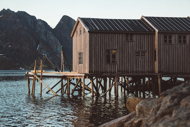山を背景に湖の近くにある古い木造の漁家。ノルウェー、ヨーロッパ。スペースをコピーします。バナーとして使用できます。