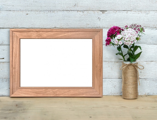 Old Wooden horizontal Frame near a bouquet of sweet-william stands on a wooden table