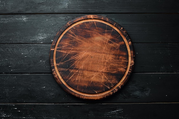 Old Wooden kitchen board on a black background Top view Free space for your text