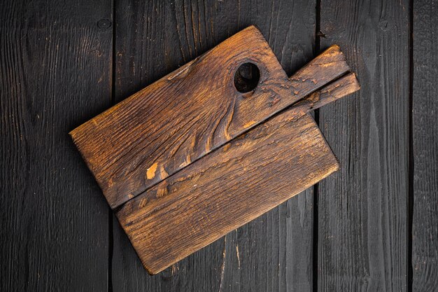 Old wooden kitchen board set top view flat lay with copy space for text or food on black wooden table background