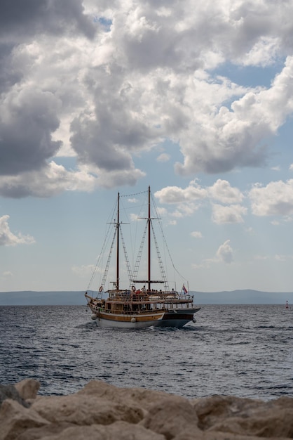 Old wooden pirate ship at sea Stormy dark clouds Mountains on the horizon