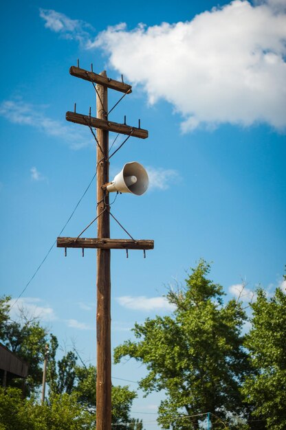 On an old wooden pole an old megaphone against the blue sky and clouds