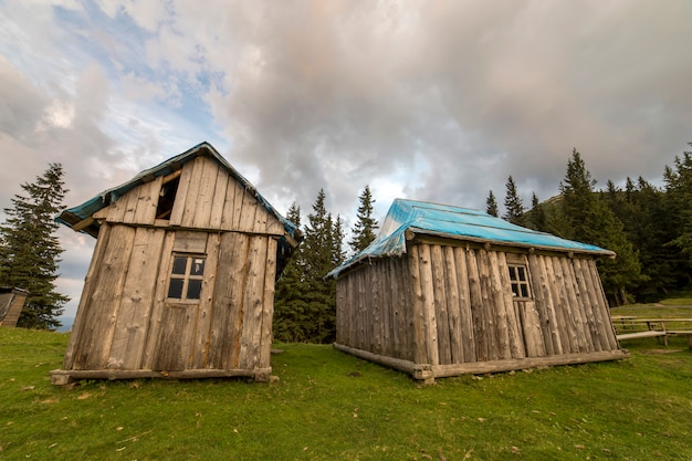 Old wooden shepherd huts on mountains green valley.