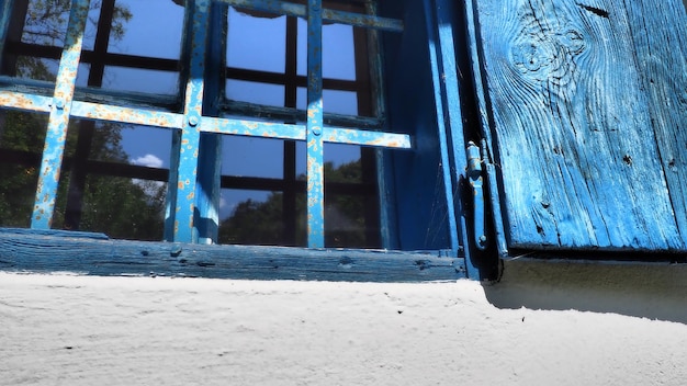 The old wooden shutters are open The wooden window frames and shutters are painted blue White concrete wall Traditional rustic architecture Glass window Trsic Loznica Serbia