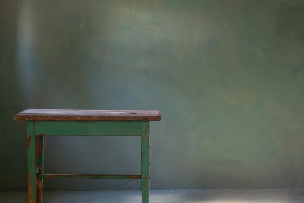 Old wooden table on background green old wall