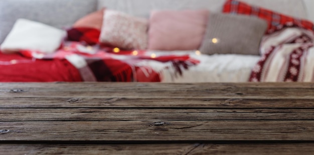 Old wooden table on background sofa with pillows and plaids