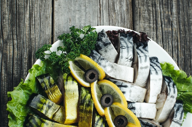 On the old wooden table beautifully on the plate is a mackerel and herring decorated