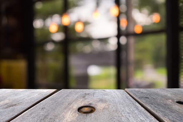 Old wooden table in front blurred coffee shop background, beautiful light and bokeh