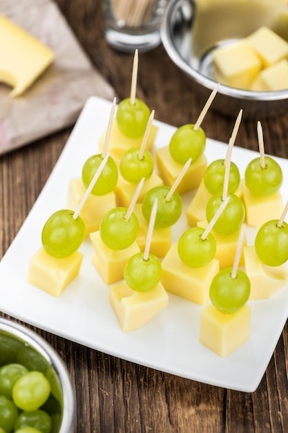 Old wooden table with Cheese blocks and grapes partyfood
