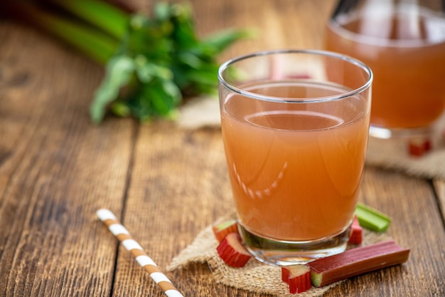 Photo old wooden table with fresh made rhubarb juice close up selective focus